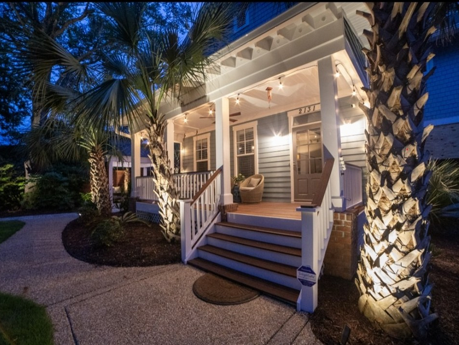 Illuminated front porch with palm trees at night