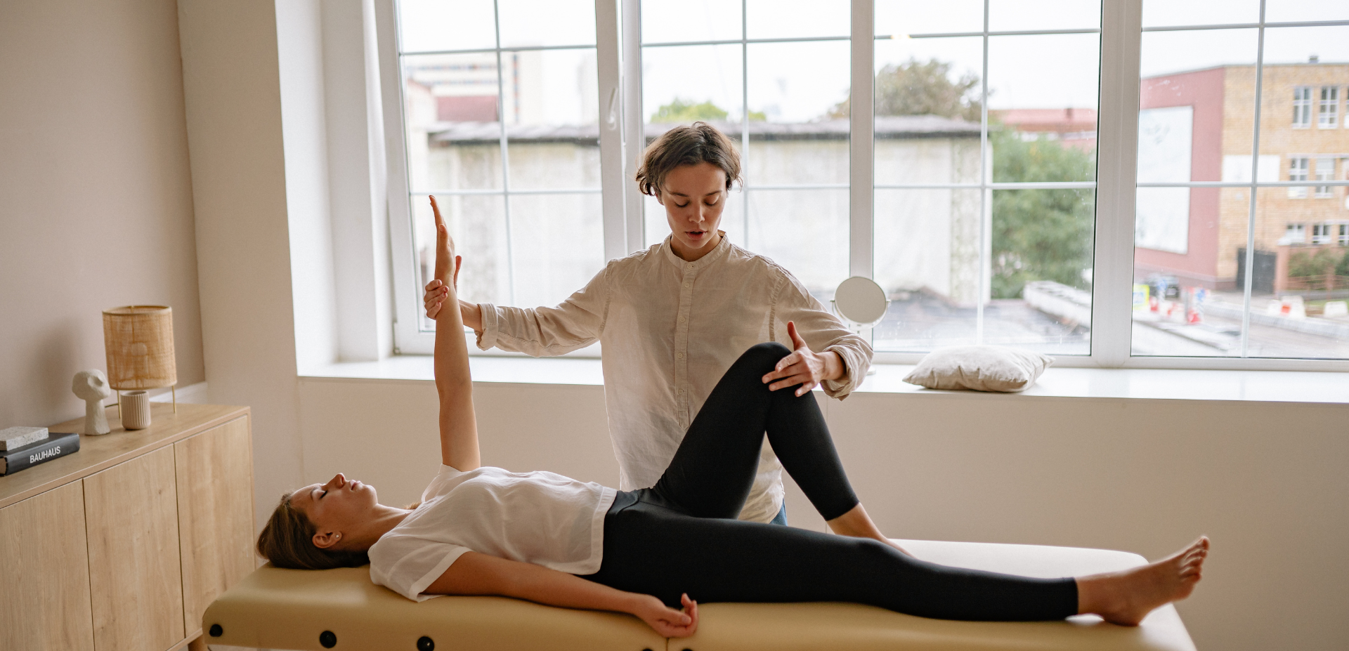 Therapist assisting patient with arm and leg stretch on massage table.