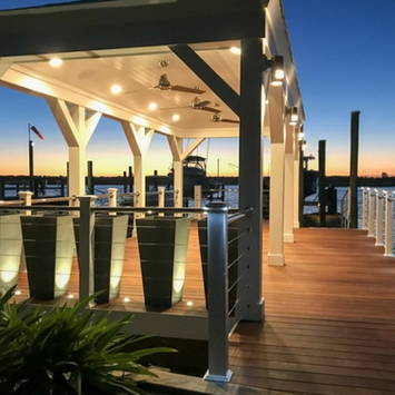 Illuminated white pavilion on a wooden dock at sunset