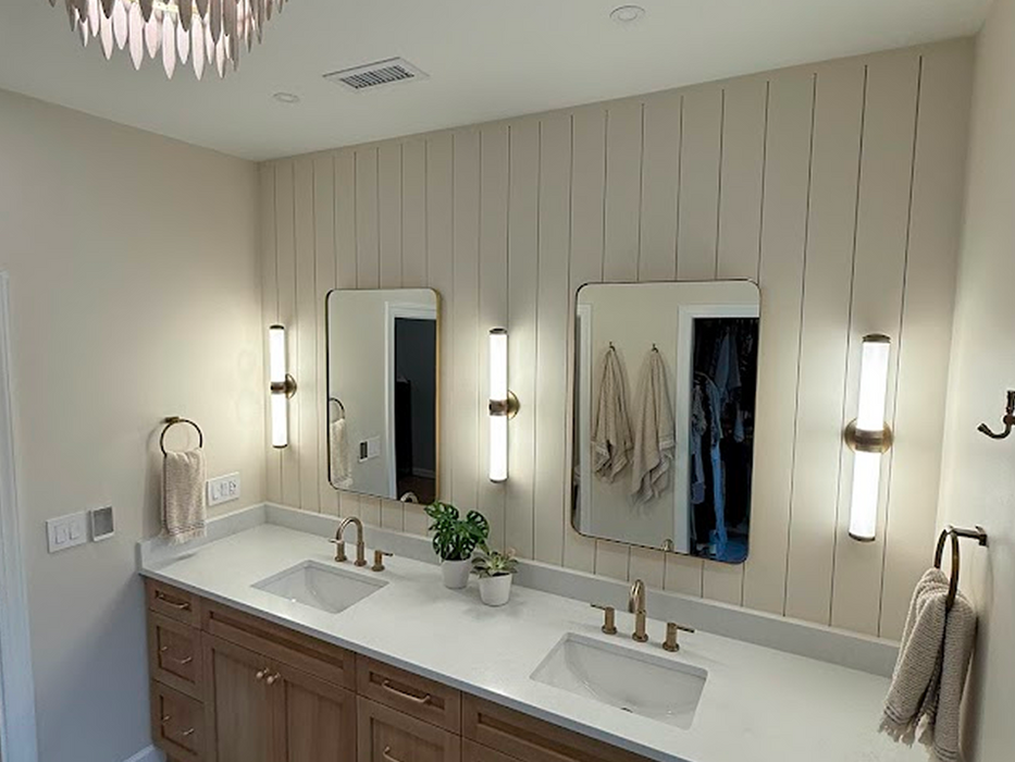 Modern bathroom vanity with double sinks and gold mirrors.