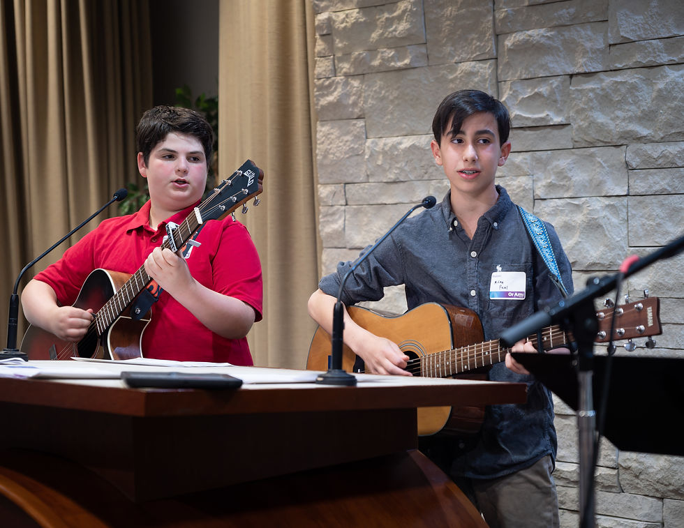 Two boys playing acoustic guitars and singing together.