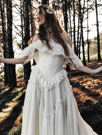 Aimery feels like something you stumbled upon and instantly knew was special. Inspired by antique embroidery and vintage craftsmanship, this Rue de Seine wedding dress features a corseted bodice layered with lace appliqué and subtle contouring that shapes without feeling overly structured.

The embroidered ruffle waistline flows into a tiered skirt that moves beautifully—romantic, but not overly precious. And with the option to wear it with or without the off-the-shoulder ruffle, this bohemian lace wedding dress can shift depending on how you want to feel—soft and romantic or a little more clean and streamlined.
