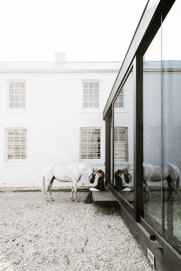 Outside of the house a girl sits with a horse
