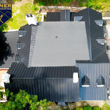 Home with a silicone flat roof system surrounded by standing seam metal, showcasing modern design and durable roofing materials.