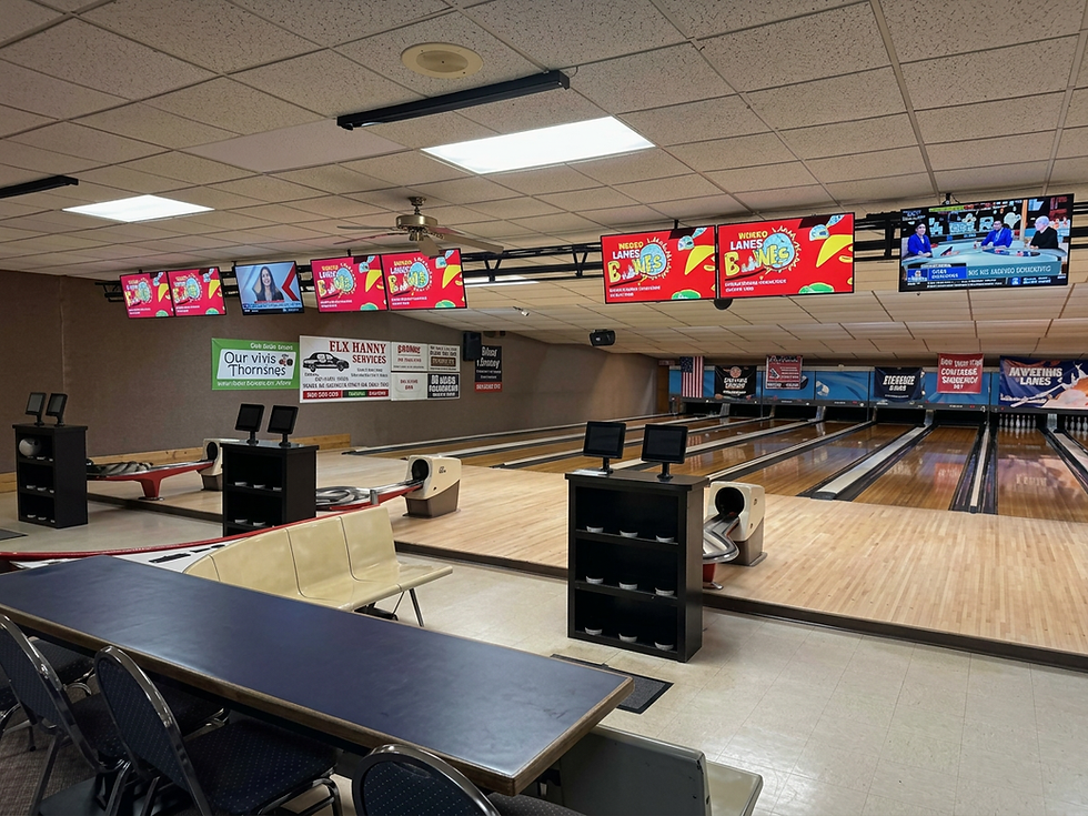 wide landscape photo of bowling lanes and seating area inside Jefferson Lanes bowling center, warm indoor lighting, colorful scoring screens above lanes