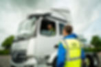man in yellow hi vis looking at silver lorry