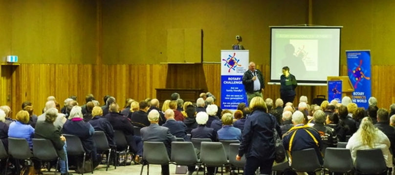 Person giving a talk with slideshow in front of a seated audience