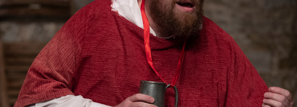 A photo of a man in a red robe holding a goblet 