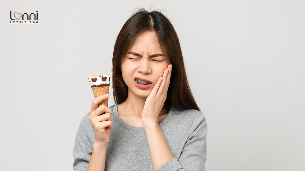 garota com sorvete na mão, de aparelho dentário,, com sensibilidade dentária e expressão de dor
