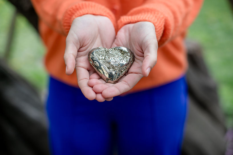 Christine Caran hält in ihrem Händen ein goldenes Pyrit Herz – werdende Eltern die ihr Baby schützen