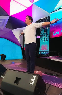 Thomas steht auf der Bühne während einer AVA Meditation on Tour und führt Teilnehmer in die AVA Methode ein