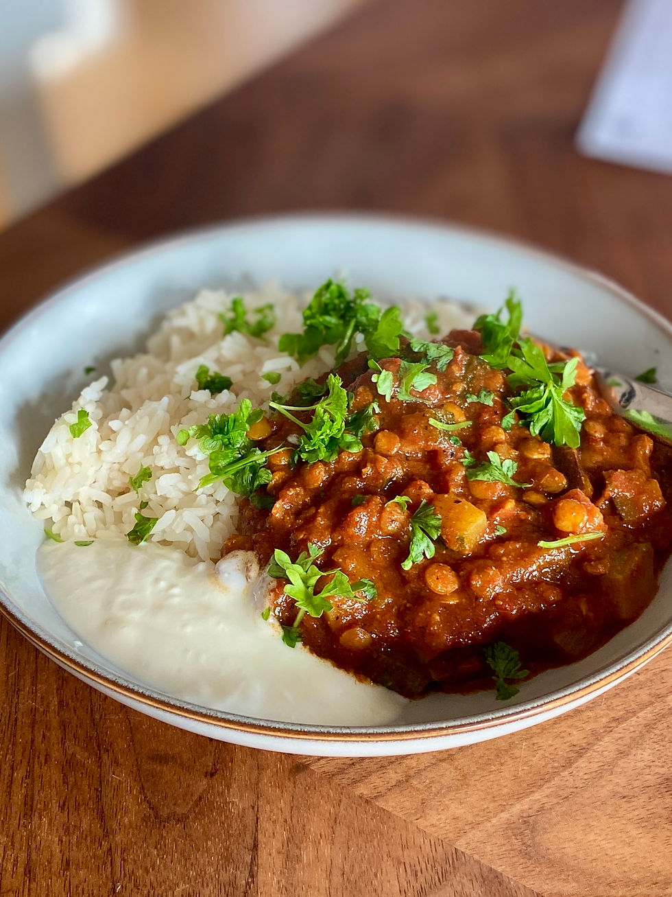Marockansk aubergine- och zucchinigryta med linser och ris serverad i en skål med vit sås