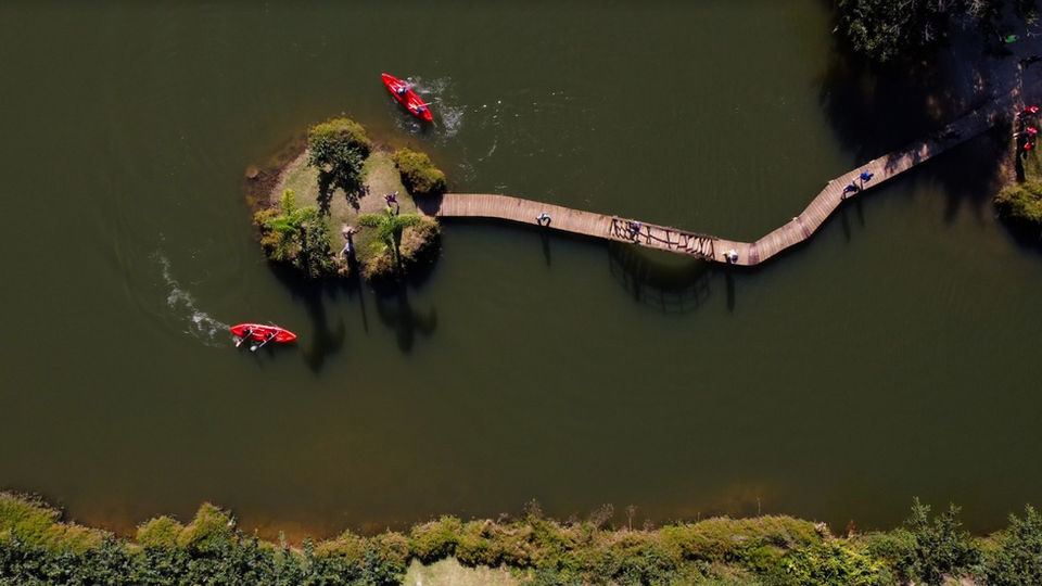 Vista de cima de lago, passarela na água e barco de caiaque do Hotel Fazenda Morros Verdes Ecolodge em Ibiúna SP
