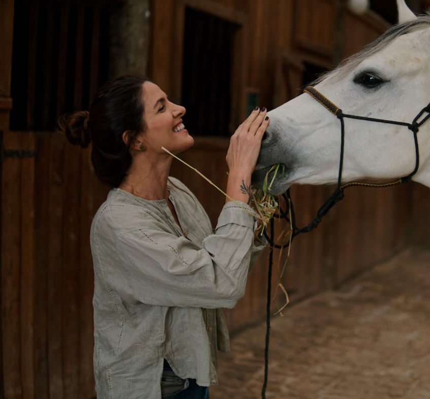 Mulher acariciando cavalo branco na Hípica Werner Haberkorn do Hotel Fazenda Morros Verdes Ecolodge em Ibiúna SP