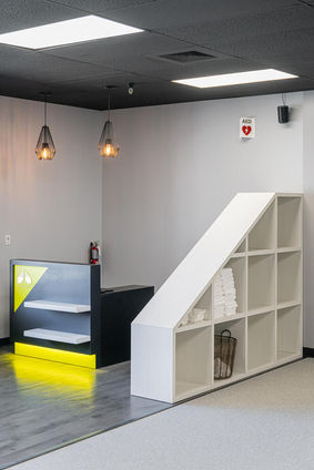 Reception and storage area at Alloy Personal Training Center featuring towel shelving and illuminated front desk – Buchanan Commercial Construction, Asheville.