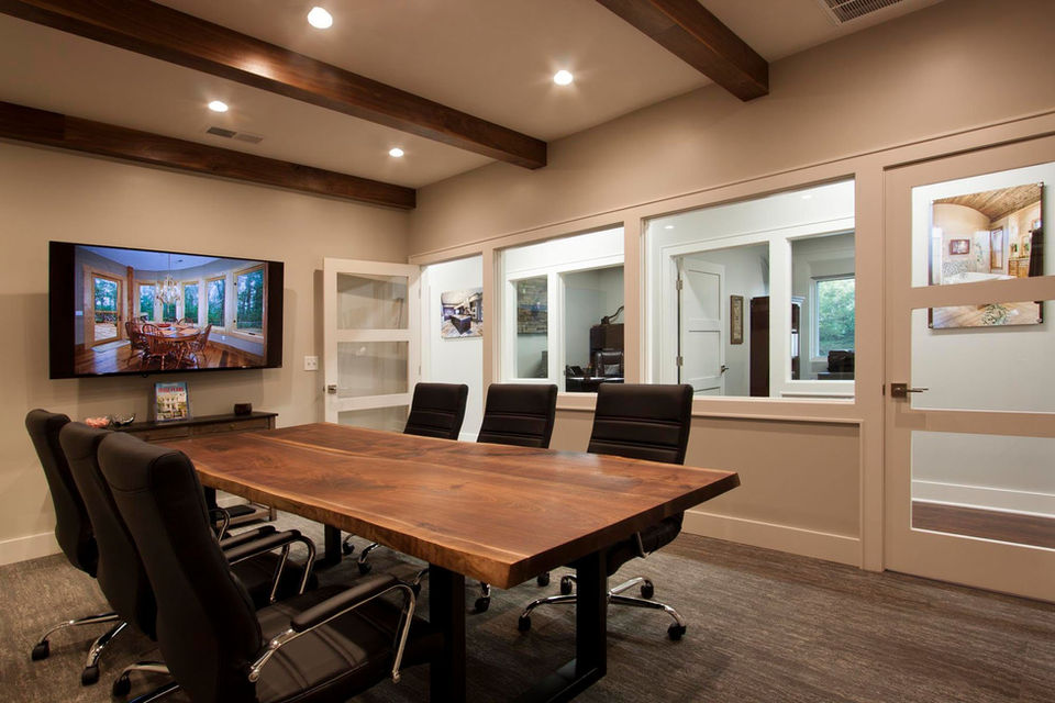 Conference room with wood table, black chairs, and exposed ceiling beams – Buchanan Commercial Construction, Asheville.