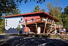 Exterior of Smoky Mountain Adventure Center with its unique industrial design, featuring red and gray panels, wood deck, and angled supports – Buchanan Commercial Construction, Asheville.