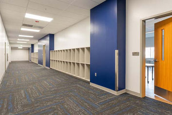 Interior hallway of Asheville Christian Academy with blue accent walls, built-in cubbies, and patterned flooring – Buchanan Commercial Construction, Asheville.