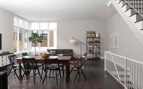 Open living and dining area with dark wood floors, modern furniture, and large corner windows – Buchanan Commercial Construction, Asheville.