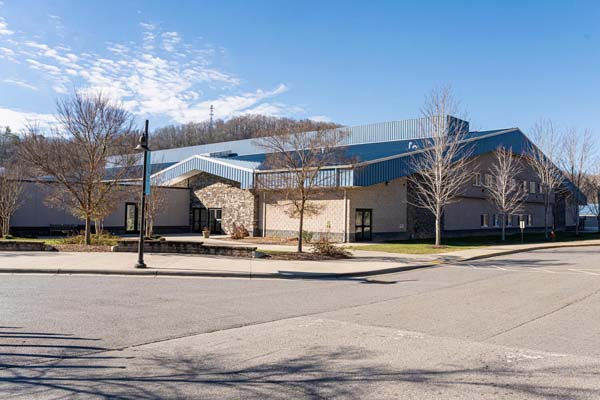 Exterior view of Asheville Christian Academy with stone and metal design under a clear blue sky – Buchanan Commercial Construction, Asheville.