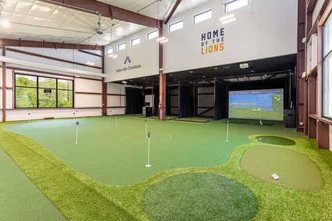 Interior of Asheville Christian Academy Golf Training Facility featuring indoor putting greens and digital golf simulators – Buchanan Commercial Construction, Asheville.
