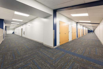 Wide school corridor with patterned carpet, blue accents, and wooden classroom doors at Asheville Christian Academy – Buchanan Commercial Construction, Asheville.