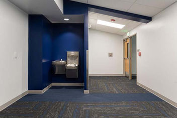 School hallway with recessed water fountains and blue accent wall at Asheville Christian Academy – Buchanan Commercial Construction, Asheville.