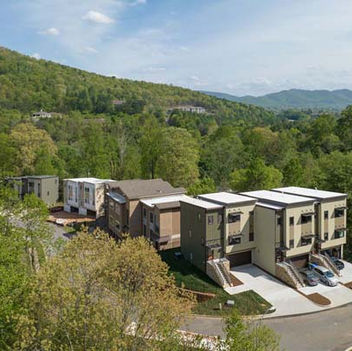 Aerial view of modern townhomes surrounded by trees and mountain scenery – Buchanan Commercial Construction, Asheville.