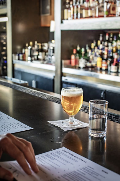 A draft beer and a glass of water at a bar.