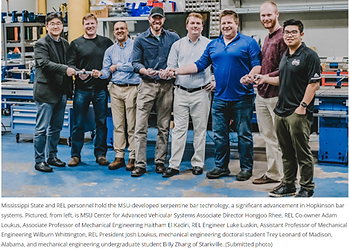 Mississippi State University IDEE Lab researchers and REL, Inc. engineers showcasing the commercial integration of the Compact Impact Wave Guide. REL’s adoption of the serpentine striker bar technology highlights academic-to-industry innovation.