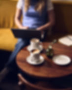 person working on a laptop at a coffee shop with two coffee on a table