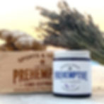 Sports cream jar labeled "Prehemptive" with lavender and ginger, next to ginger root and dried lavender, on wooden box. Warm background.