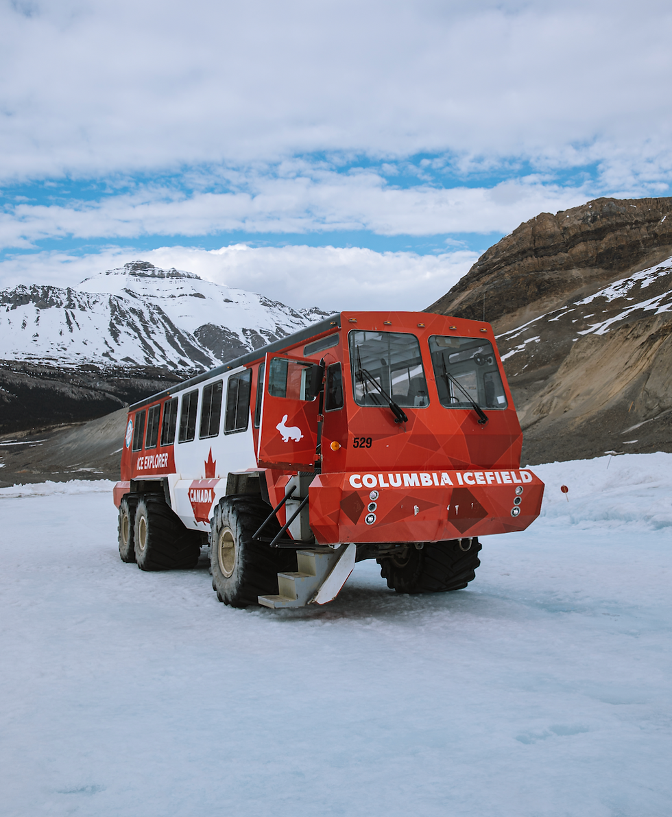 Red ice explorer vehicle on snowy terrain at Columbia Icefield. Snowy mountains in background, overcast sky above. Canada and rabbit logos visible.