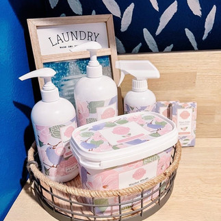 Scentsy laundry products in a basket on a floor.