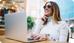 pensive-smiling-young-woman-using-laptop-table-street-cafe 1