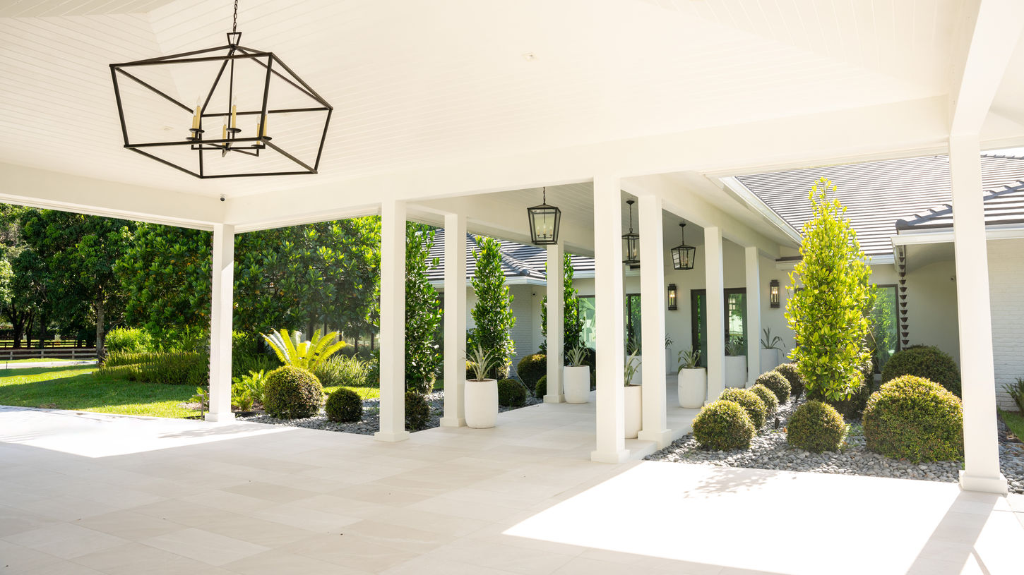 Grand entrance to The Reserve of Southwest Ranches featuring covered architectural walkways, manicured landscaping, and luxury estate design.