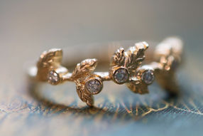 Hand carved yellow gold leaf motif ring with 6 round bezel set lab grown diamonds along the length of the ring.