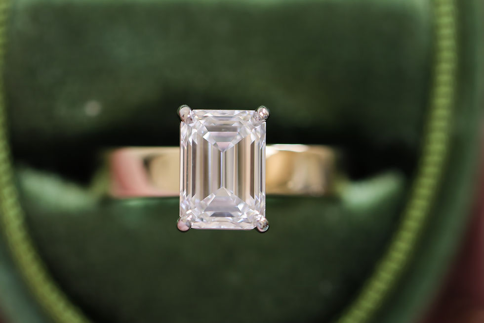 Emerald cut solitaire engagement ring with a thick, heavy yellow gold band.