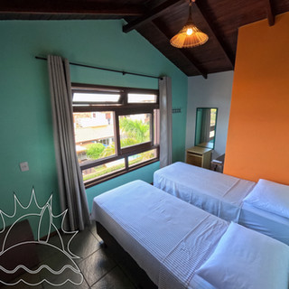 Habitación con dos camas individuales y una ventana grande.