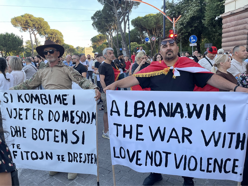 Protestors on Tirana’s Martyrs of the Nation Boulevard on June 13, 2026. The sign on the left reads: “As the oldest nation, we will teach the world how to win justice.” The one on the right stands out as particularly poignant after protests escalated this October, leading to a drastic police response. Eleftheria Kousta / Arbanon Magazine.