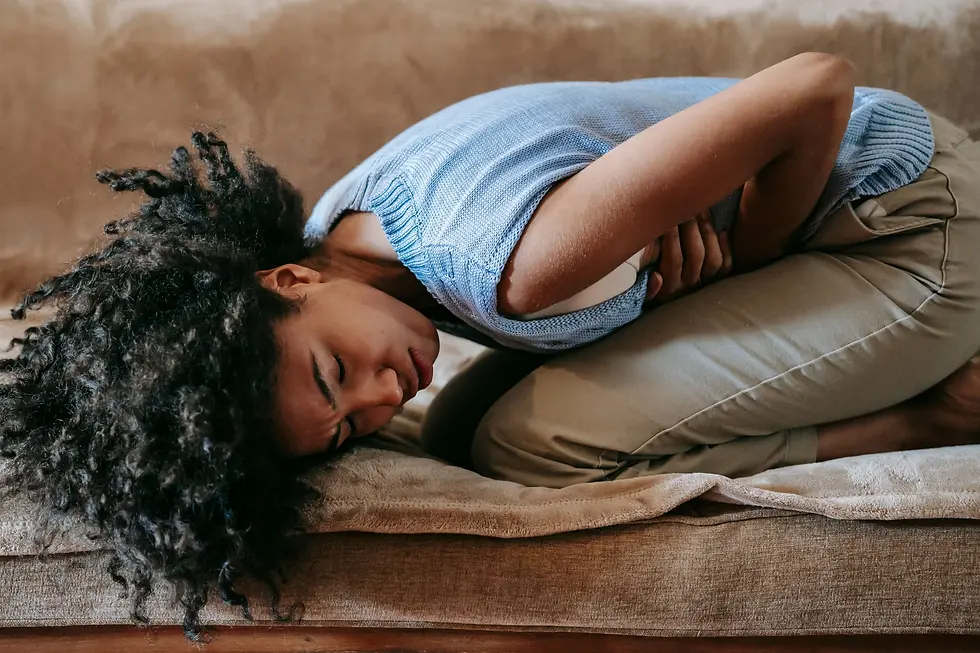 Femme allongée en position recroquevillée, une main sur le ventre, souffrant de douleurs abdominales