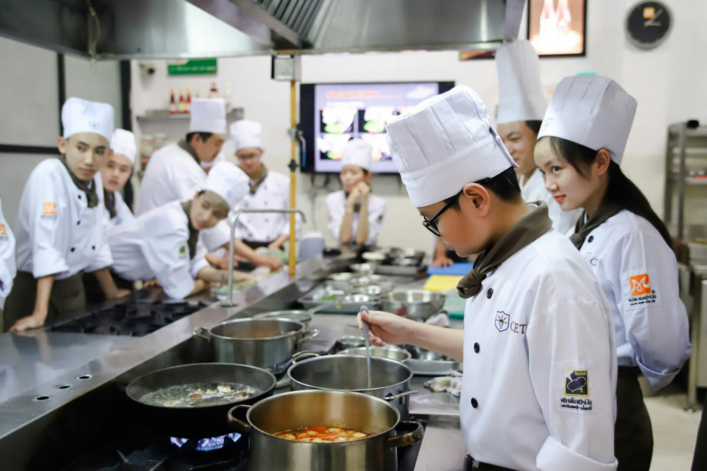 Chefs working at cooking pots in a commercial kitchen