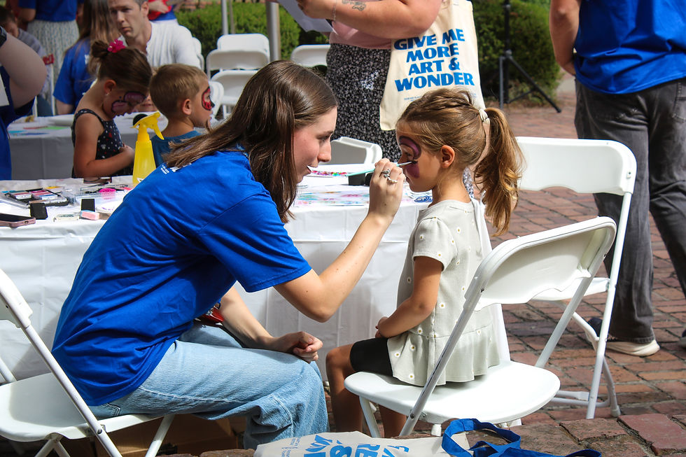 A student volunteer face paints a girl's face in the face-painting section of the Kids Zone. (Kate Basler)