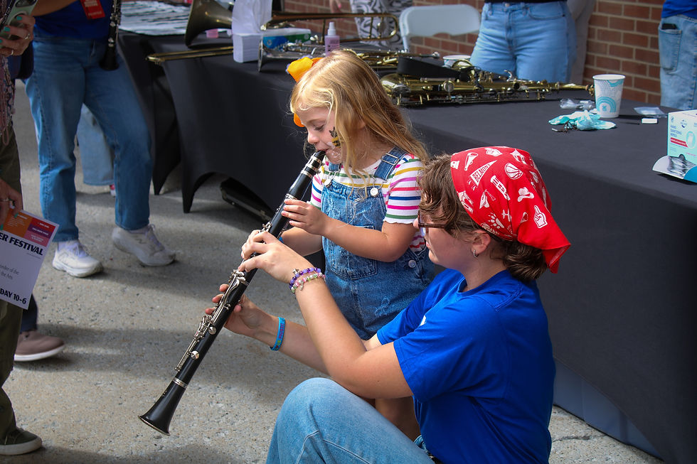 Sophomore Music Education major Ainsley Mahoney teaches a girl how to play the clarinet. (Kate Basler)