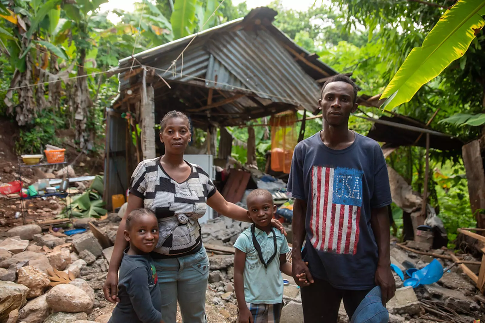 A family standing outside of their wrecked home in the village of Marceline, near Les Cayes, Haiti.