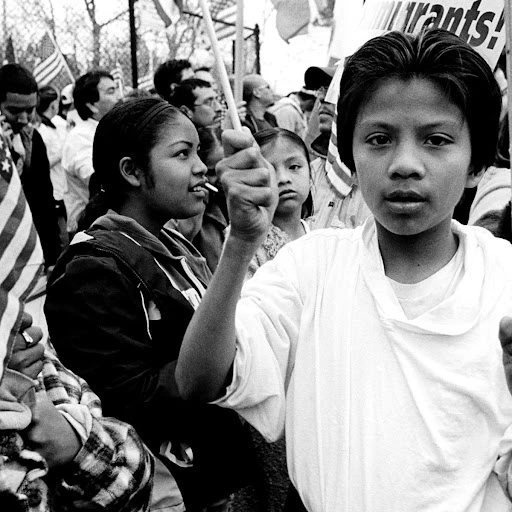 A hispanic boy holding a flag at a rally.