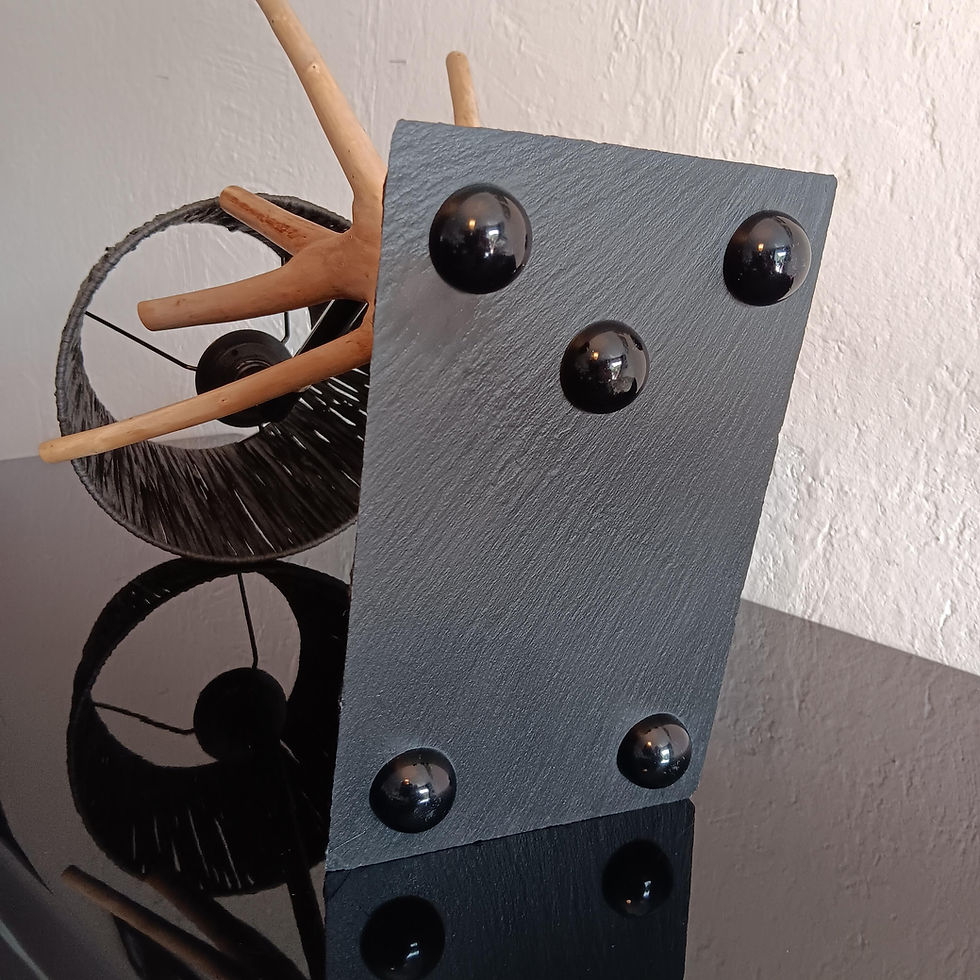 Miniature : Objet noir avec des sphères, reflet sur table noire, décoration en bois derrière.