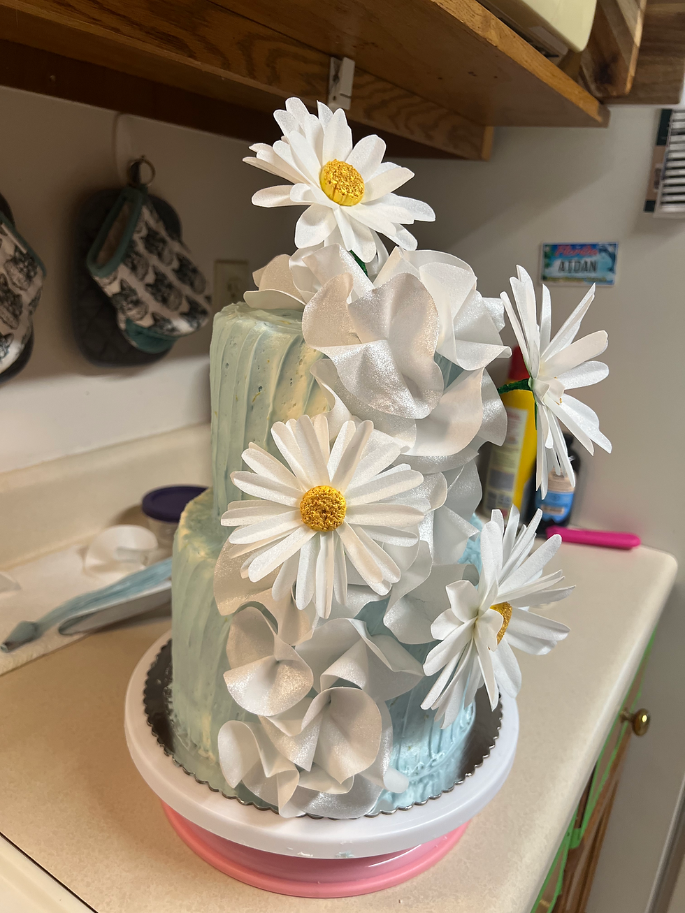 A two tiered cake with handcrafted wafer paper daisies and ruffles.