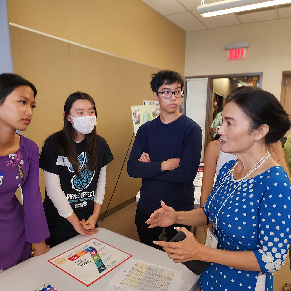 Three Milpitas students talking with Hon Lien at a community event.