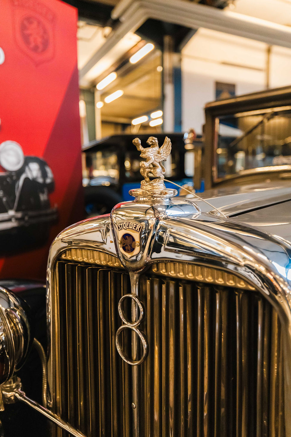 Nahaufnahme des Kühlergrills eines Stoewer Automobils in der Sammlung AUTOMOBIL des PS.SPEICHER. Im Fokus steht der Greif als Stoewer-Emblem und als Kühlerfigur auf der glänzenden Chromfront.